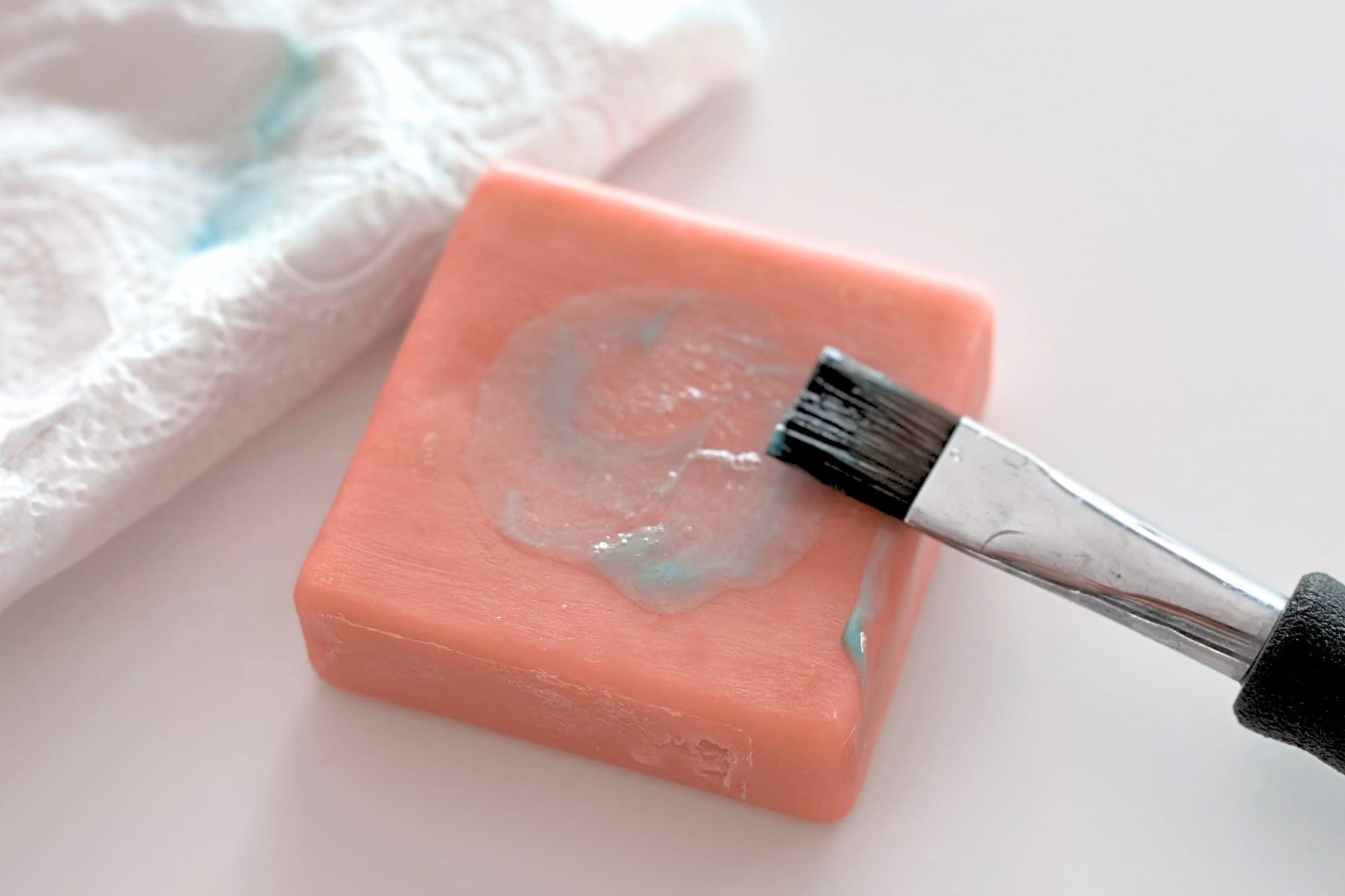 A watercolor brush being cleaned on a bar of brush soap